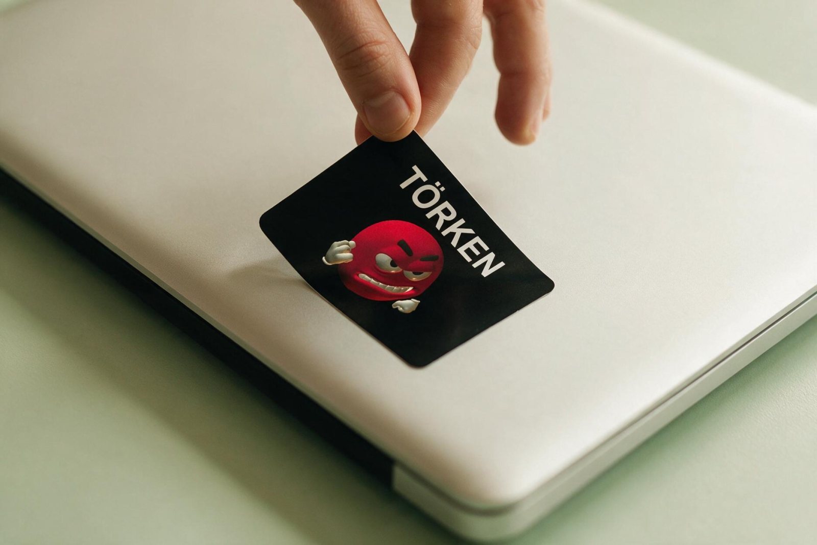 Der Törken-Sticker wird in flachem Winkel vom Laptopdeckel abgezogen